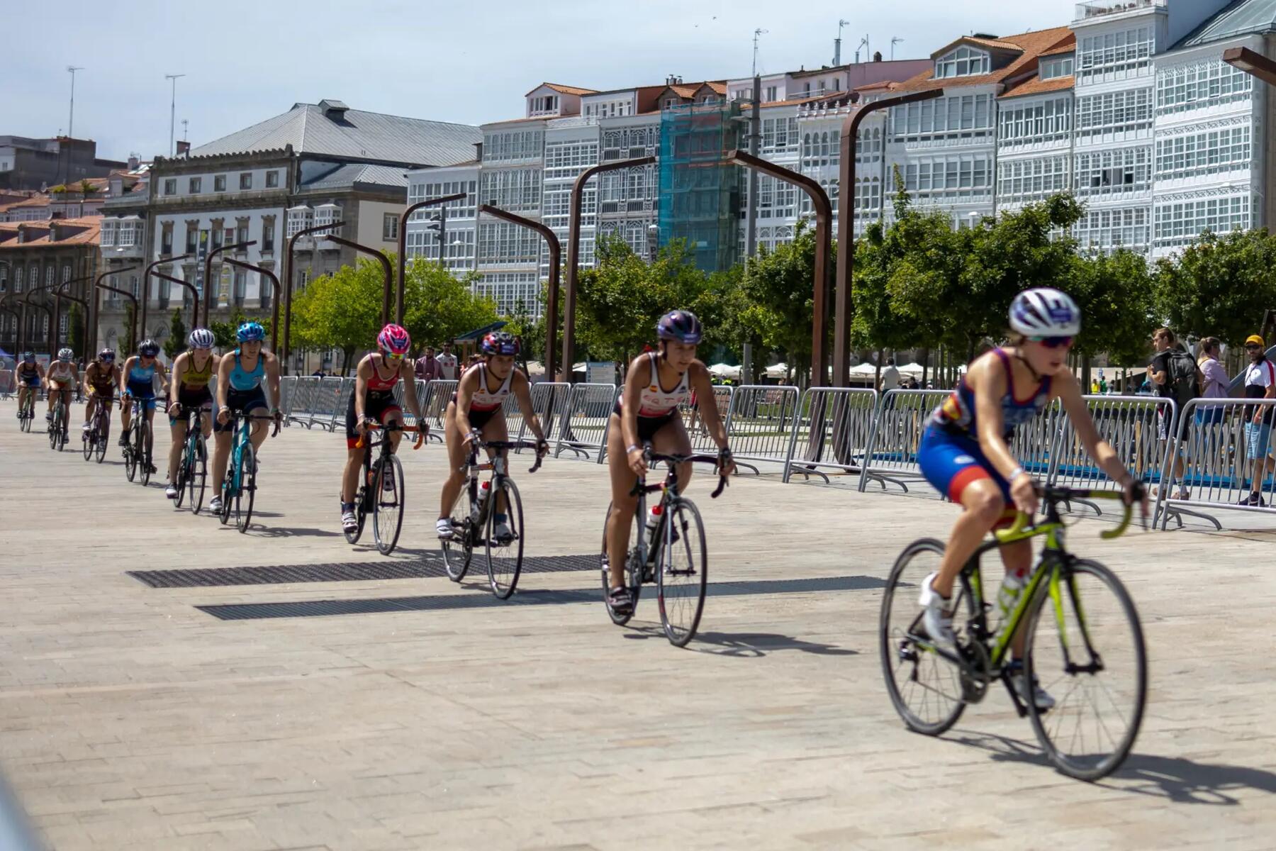 Kobiety w kaskach i w okularach jadące na rowerach w triathlonie