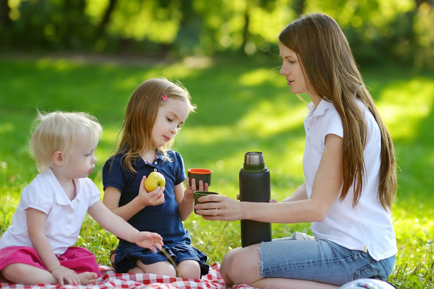 Mama z dziećmi na kocu podczas pikniku