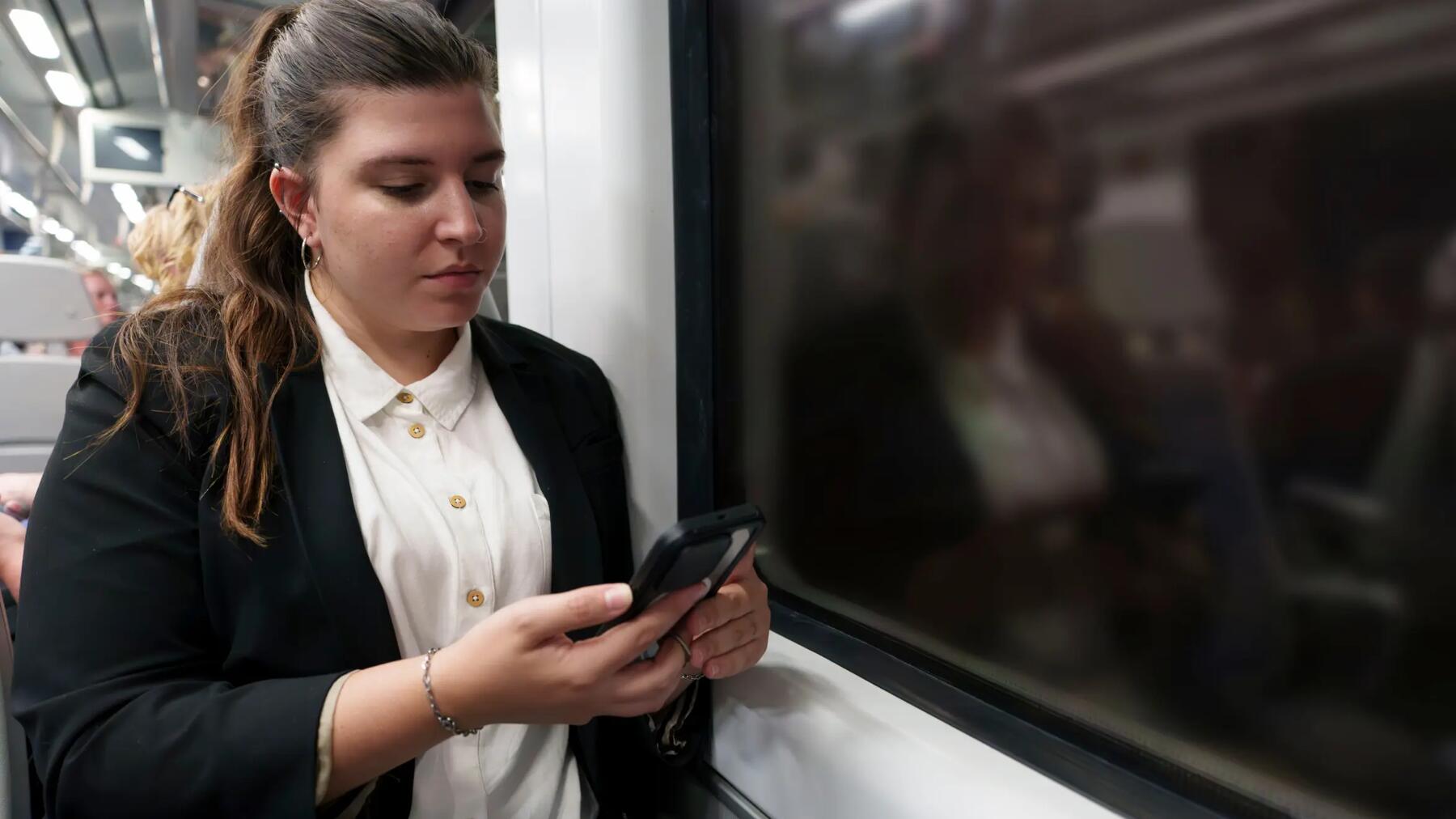 Kobieta trzymająca telefon jadąc w pociągu nocą