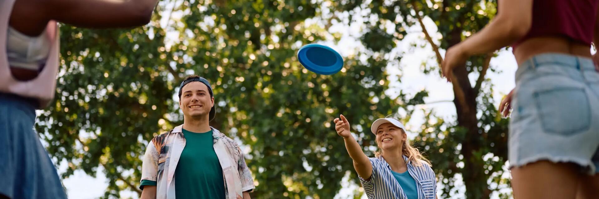Grupa znajomych grająca we frisbee w parku