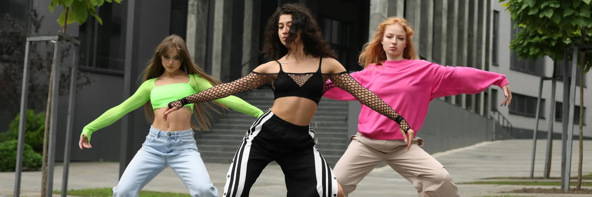 Trzy dziewczyny w odzieży sportowej tańczące hip-hop na dworze