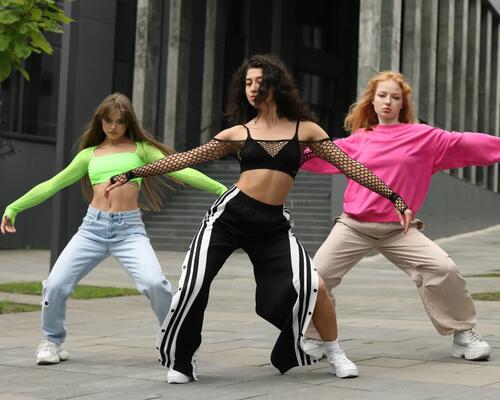 Trzy dziewczyny w odzieży sportowej tańczące hip-hop na dworze
