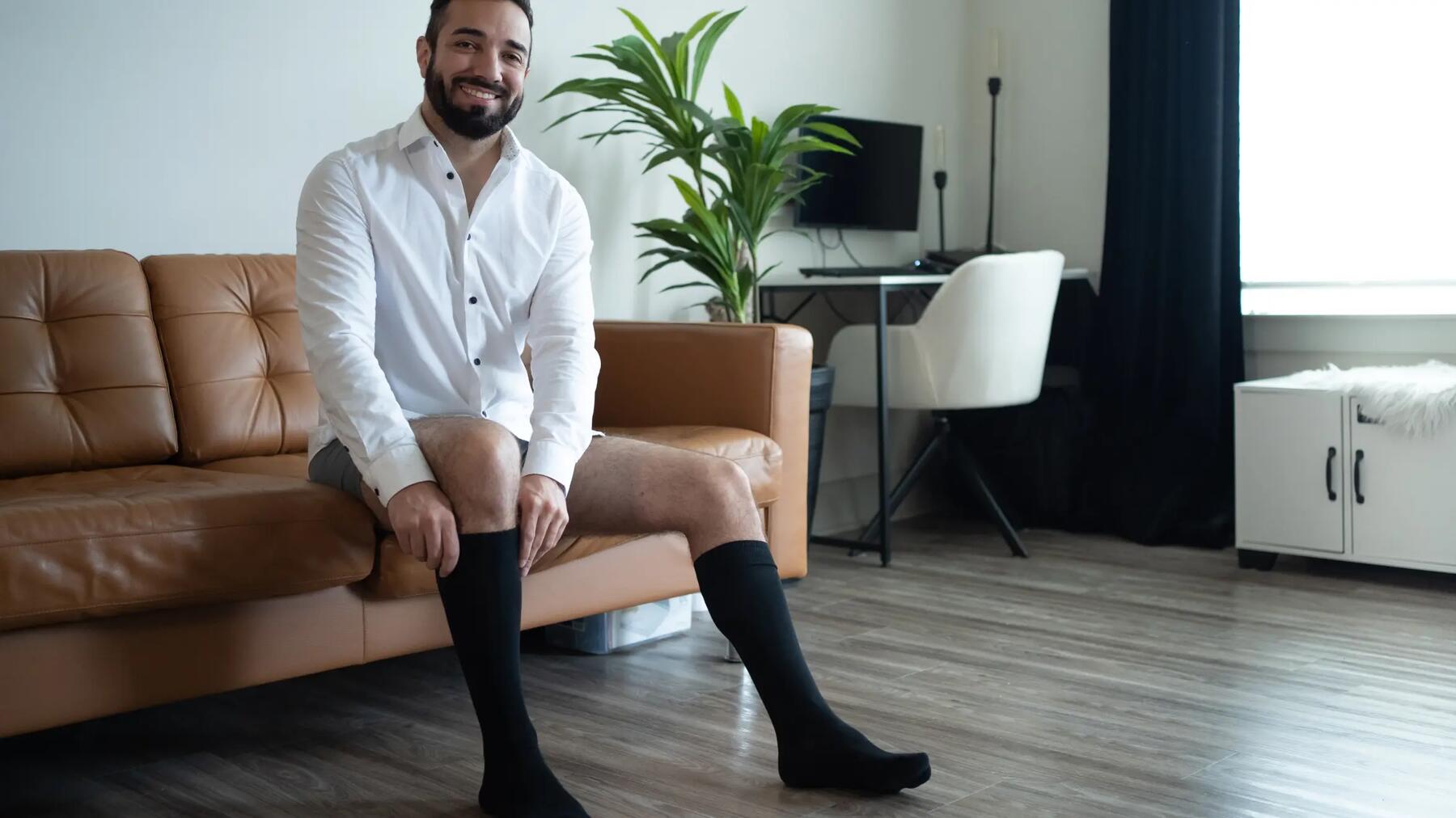 Mężczyzna siedzący na kanapie ubierający długie skarpety