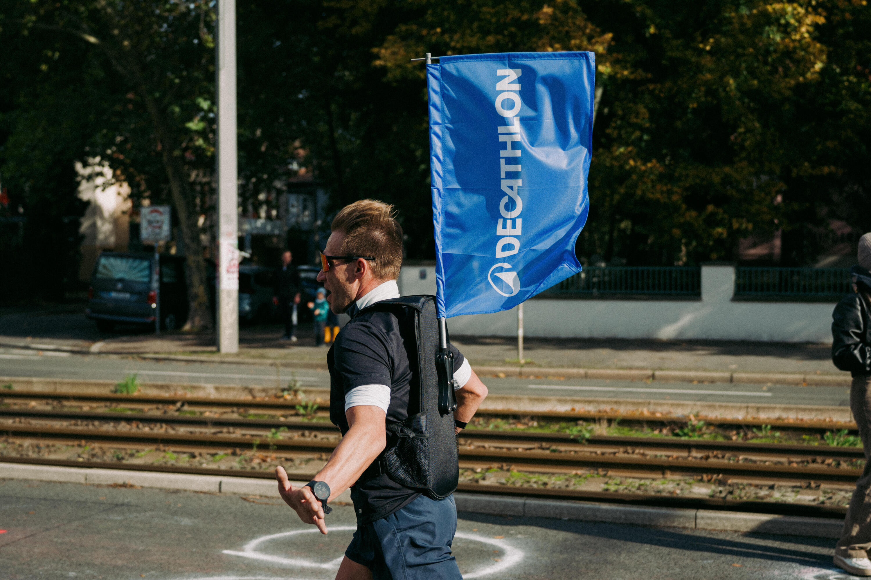 Ein Mann rennt mit einer Decathlon Fahne im Rucksack auf dem Rücken.