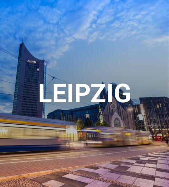 Ein weißer Leipzig Schriftzug im Vordergrund und der Stadt im Hintergrund.