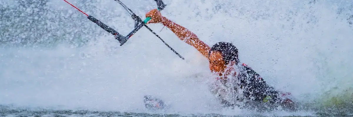 Osoba próbująca wykonać body dragi w wodzie trzymając bar do kitesurfingu