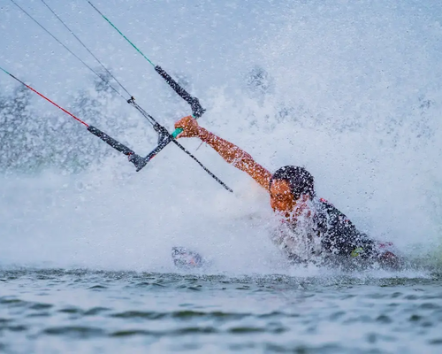 Osoba próbująca wykonać body dragi w wodzie trzymając bar do kitesurfingu