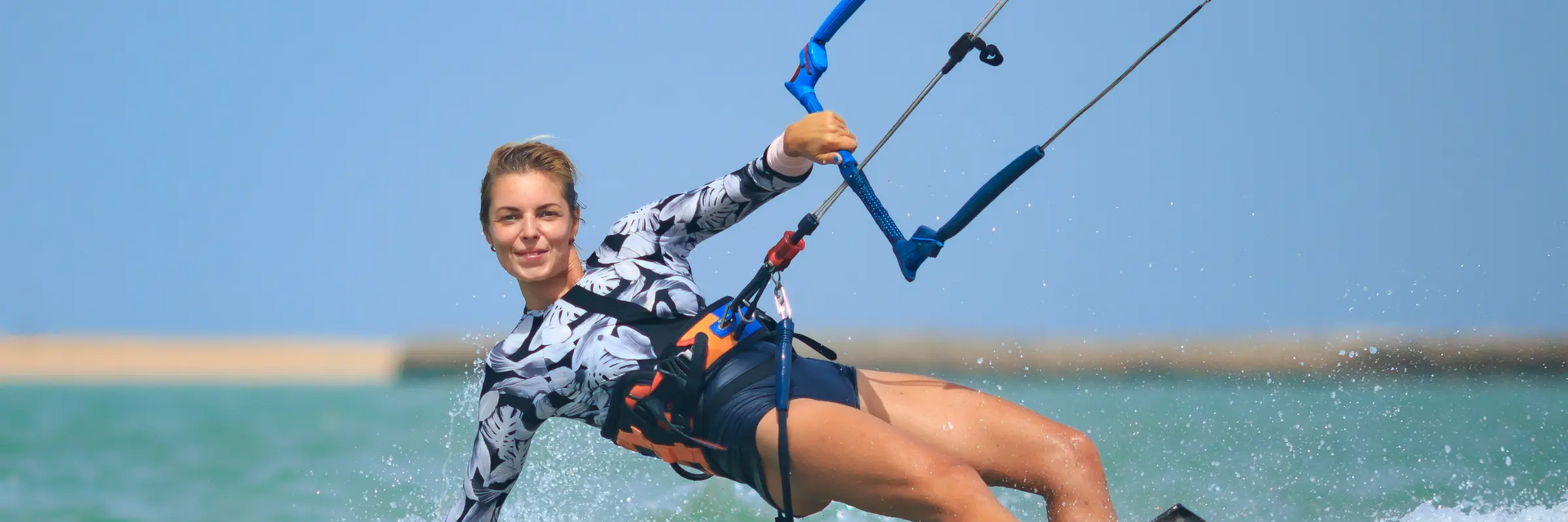 Kobieta w stroju do kitesurfingu trenująca kitesurfing ze zrywką bezpieczeństwa