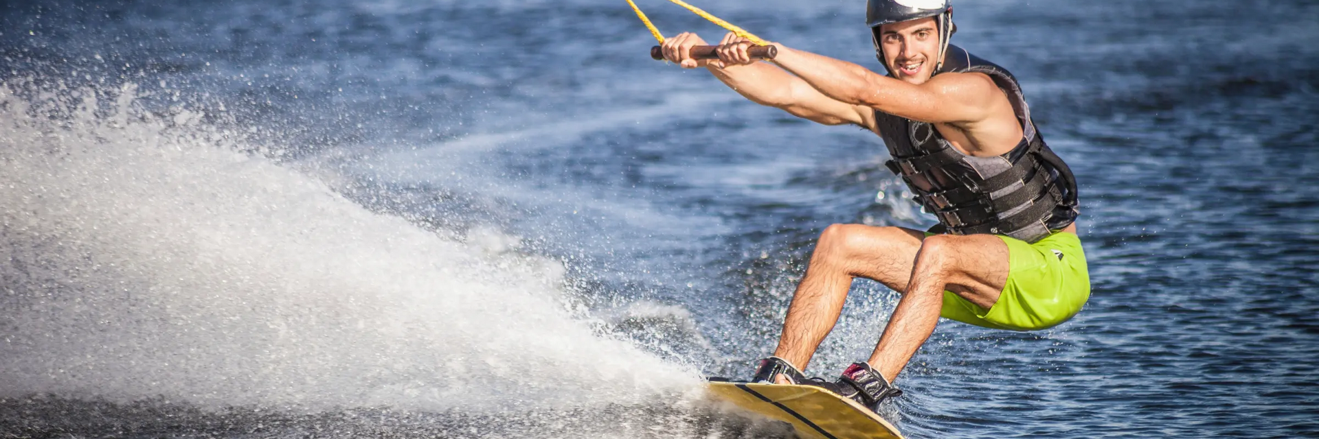 mężczyzna w kasku i kamizelce do wakeboardu trenujący wakeboarding 