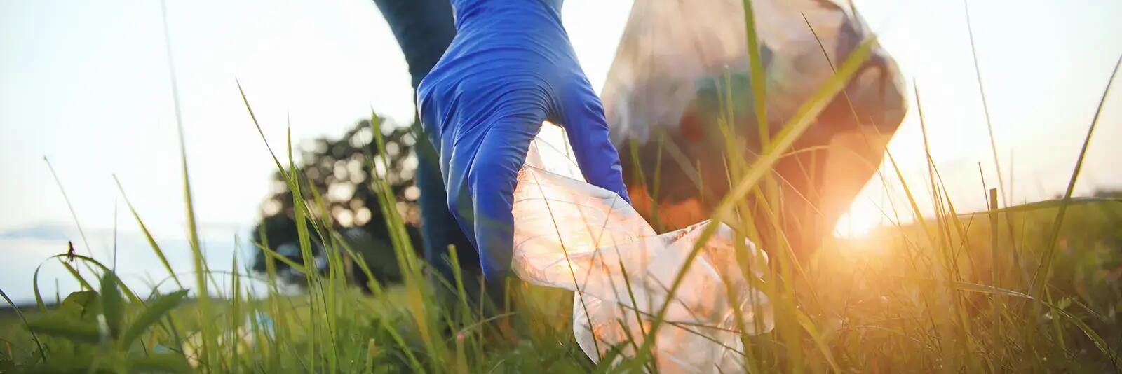 Mężczyzna w rękawiczkach zbierający śmieci z trawy podczas światowego dnia ziemi