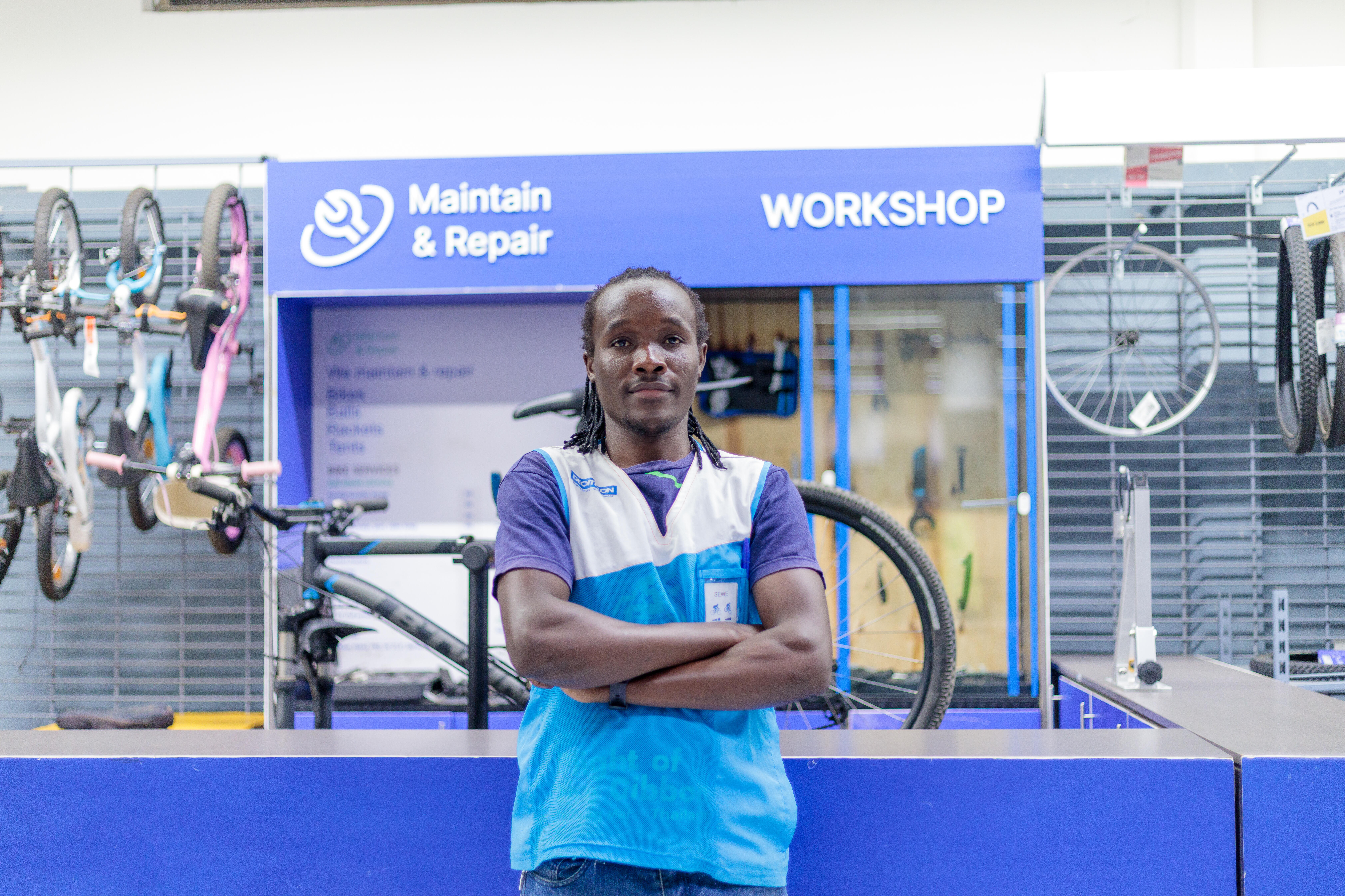 A salesperson at a Decathlon store helps a customer with a bike while they consult about the bike's options or settings.