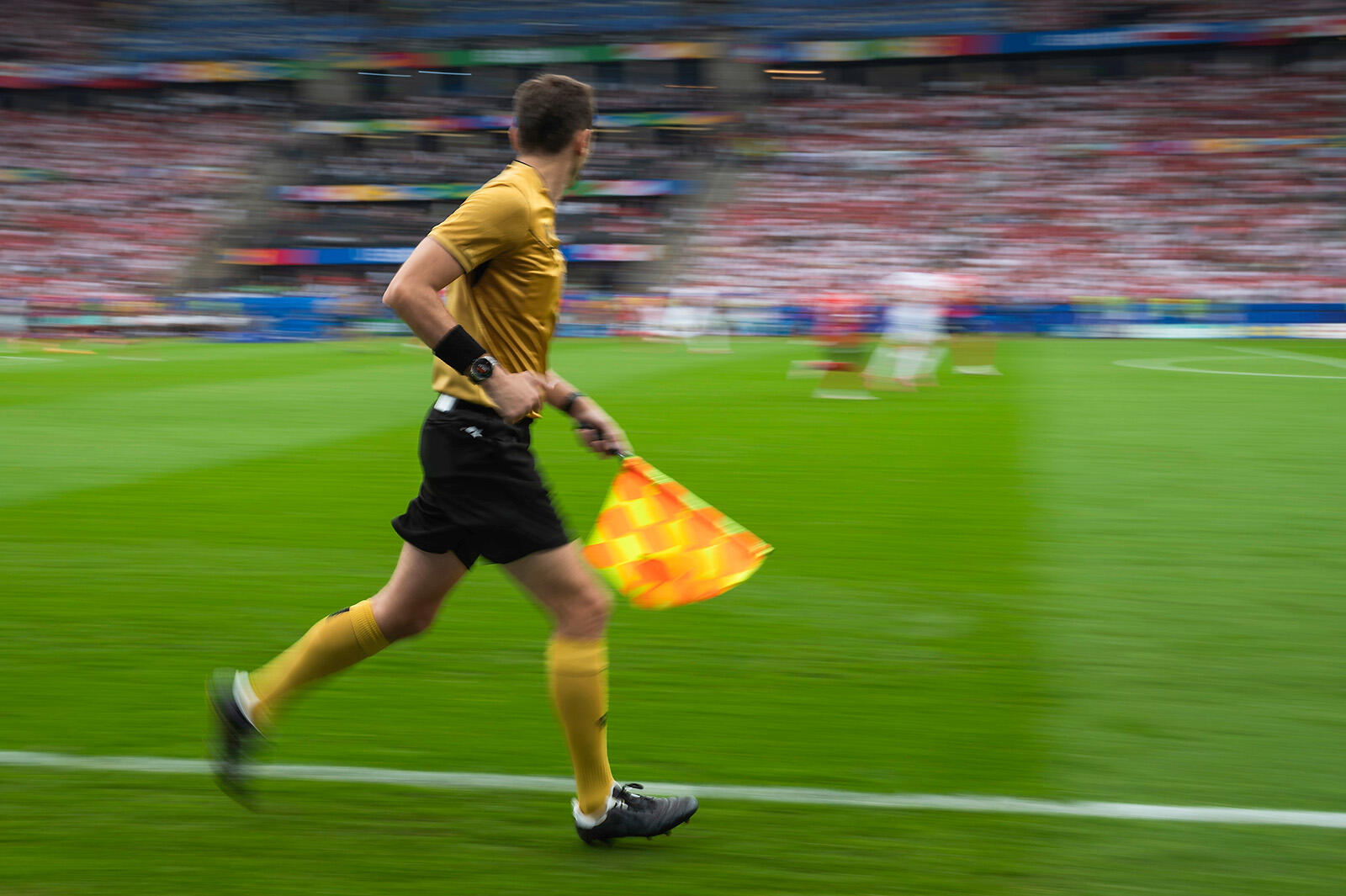 Sędzia piłkarski biegnący z flagą wzdłuż boiska