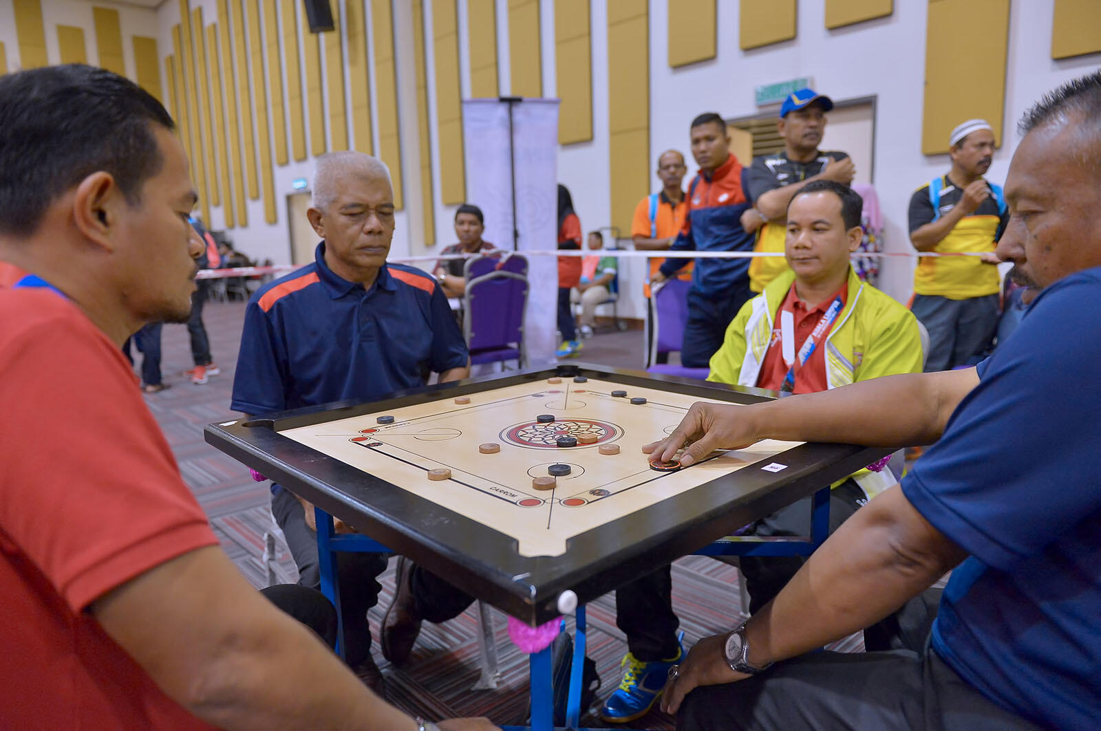 Mężczyźni siedzący przy stole grający w carrom