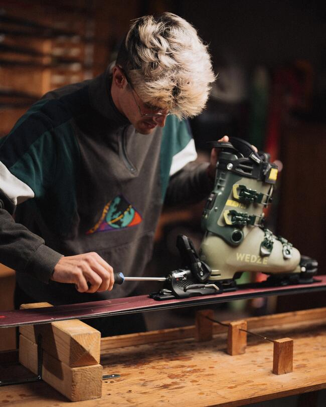 personne qui fixe une chaussure de ski