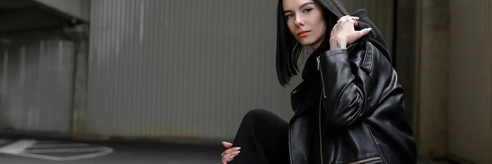 Kobieta w ramonesce i w dresach siedząca na krawężniku