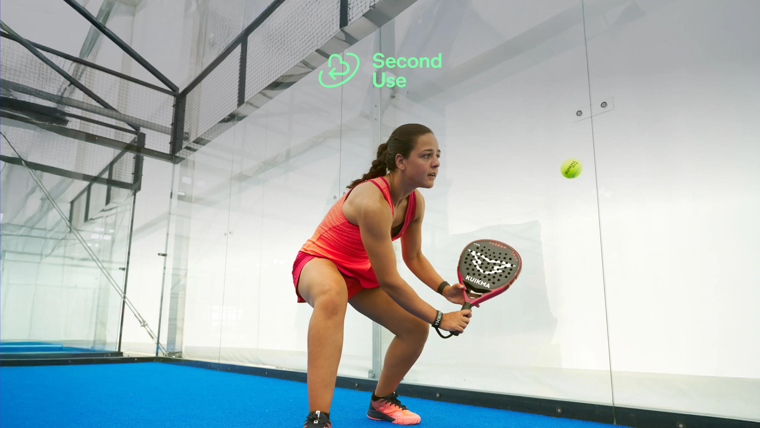 Eine Frau, die auf einem Indoor-Court Padel spielt.