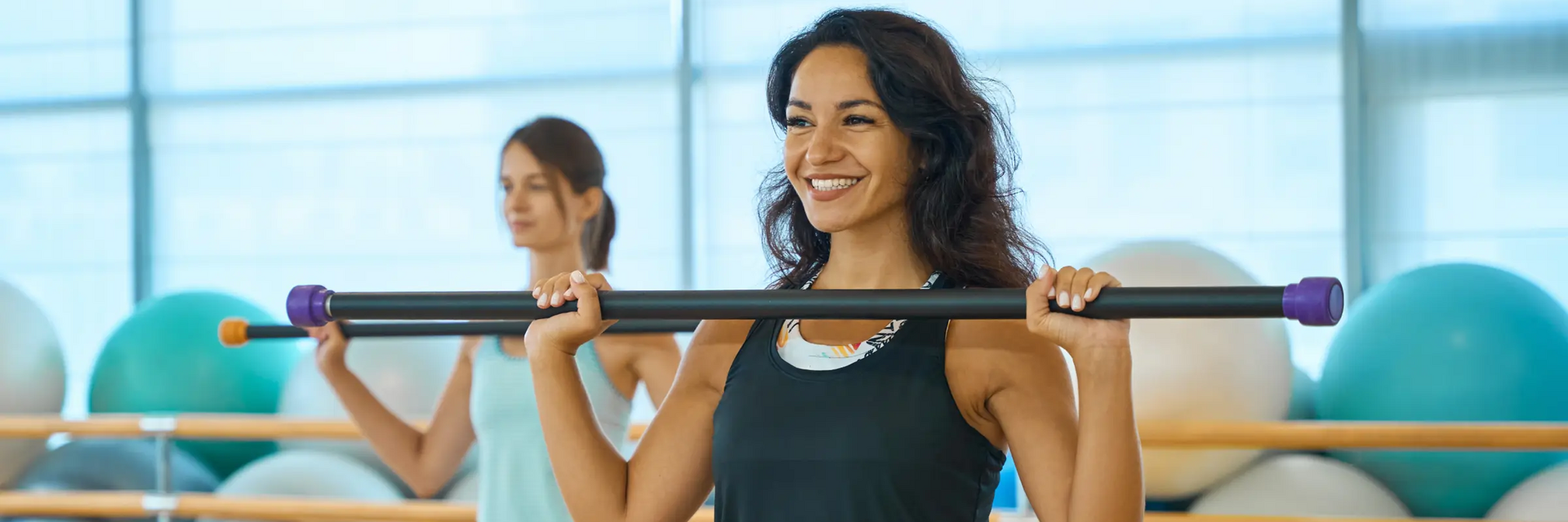 Kobiety ćwiczące z drążkiem do pilatesu na sali