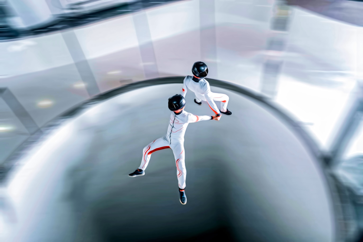 Dwoje ludzi trzymających się za ręce podczas lotu w tunelu aerodynamicznym