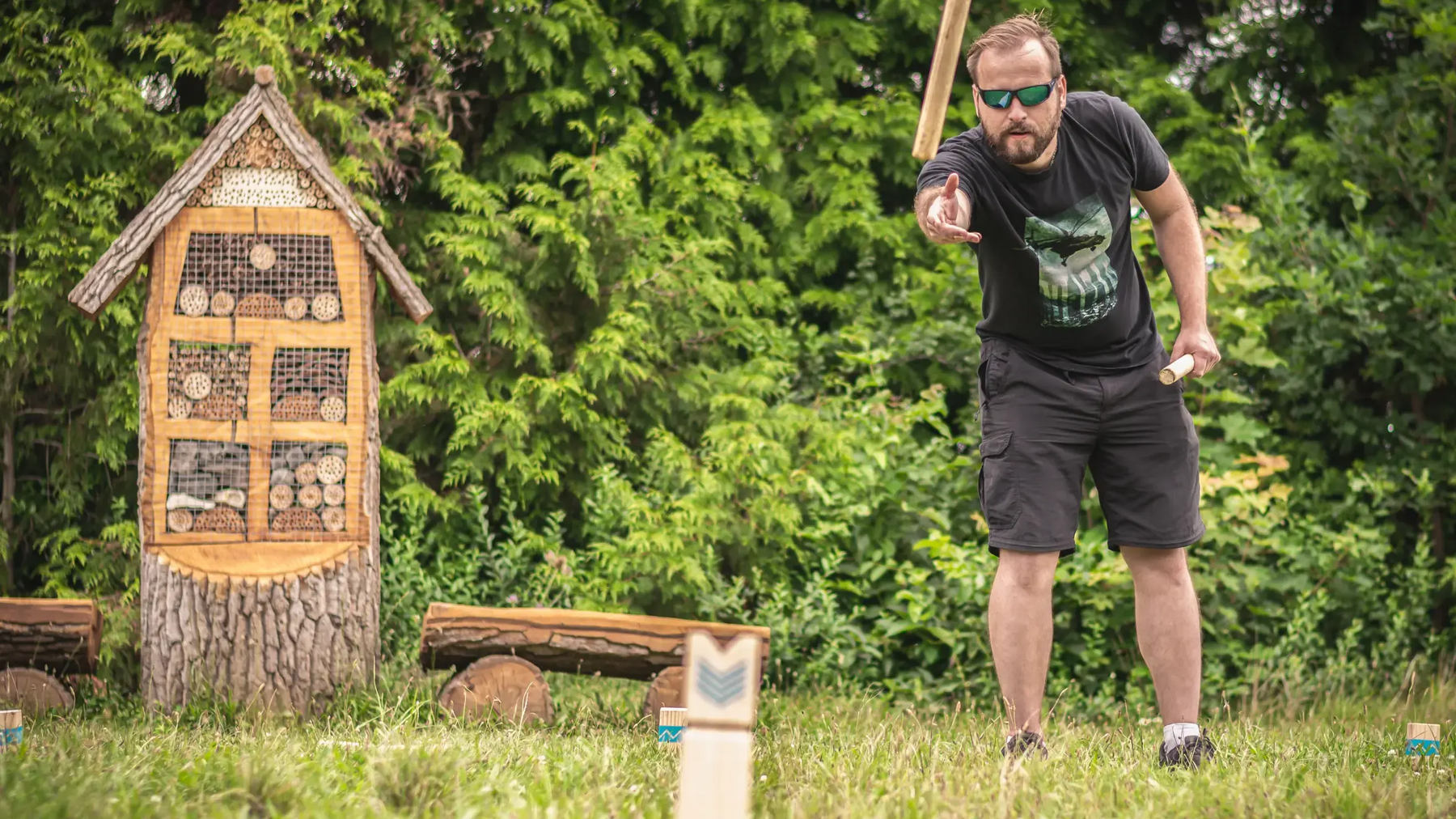 Mężczyzna rzucający pałką w klocki kubb na trawie