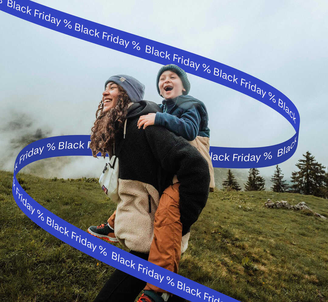 Mati nosi sina na hrbtu na gorski jasi, okoli njiju pa je trak z napisom popusti za Black Friday.