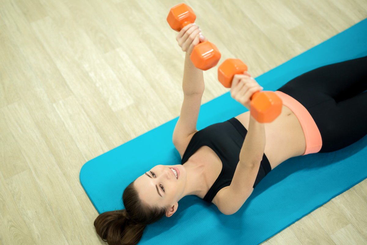 Kobieta ćwicząca na macie pilates z hantlami