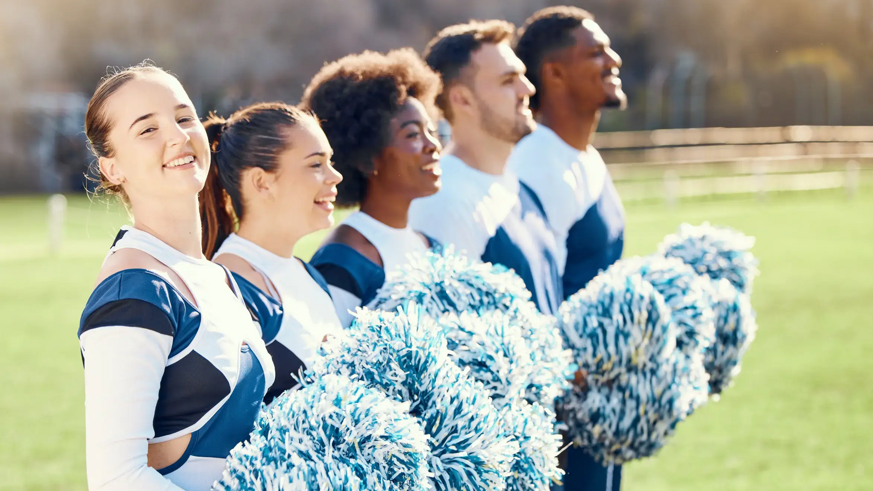 Cheerleaderzy i cheerleadkerki stojący z pomponami