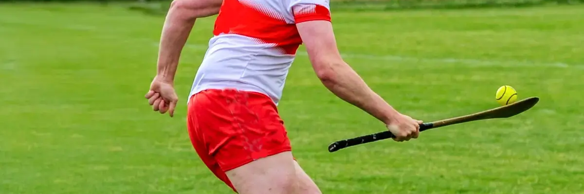 Mężczyzna biegnący z hurley i piłką grający w hurling