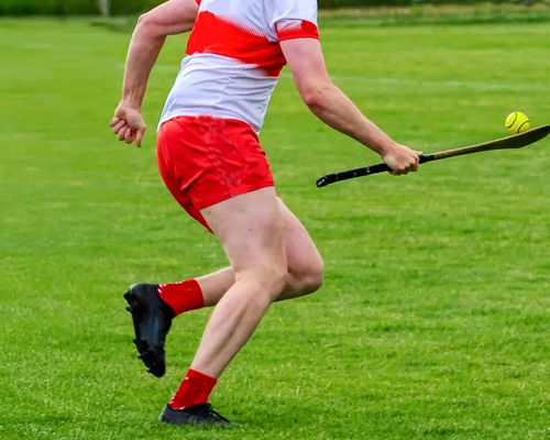 Mężczyzna biegnący z hurley i piłką grający w hurling