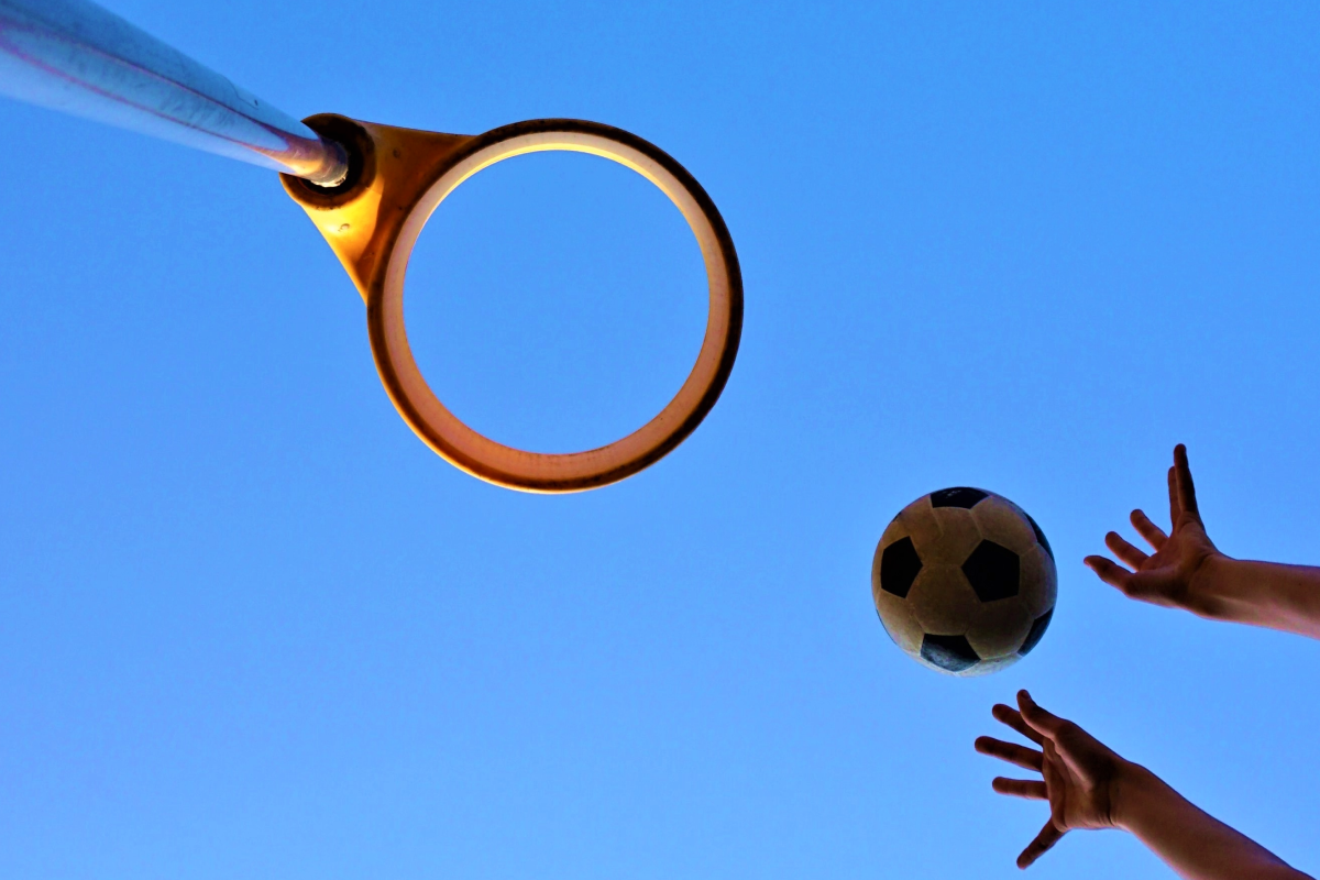 Osoba wrzucająca piłkę do kosza podczas gry w korfball