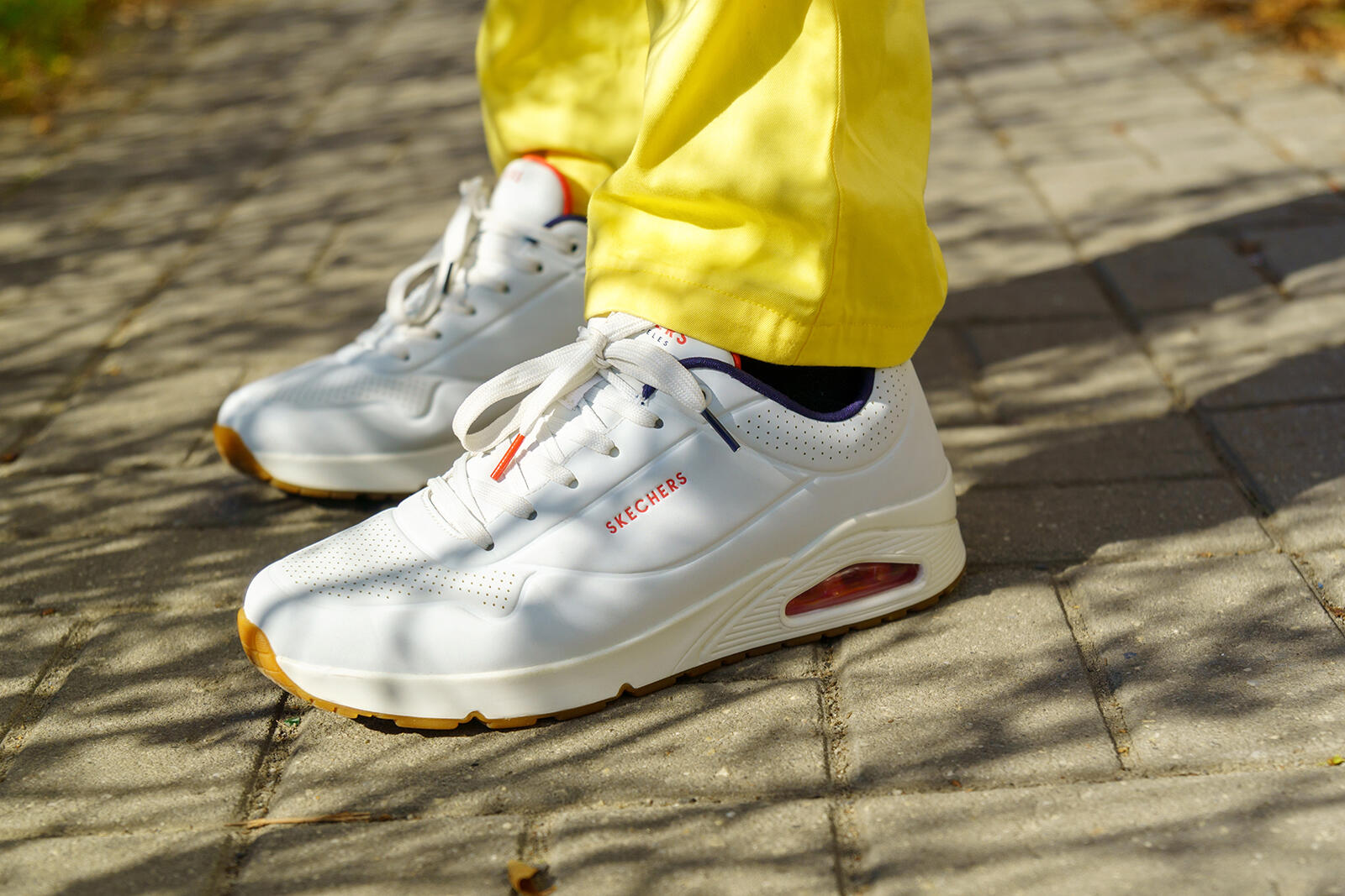 Osoba w adidasach Skechers na nogach stojąca na chodniku