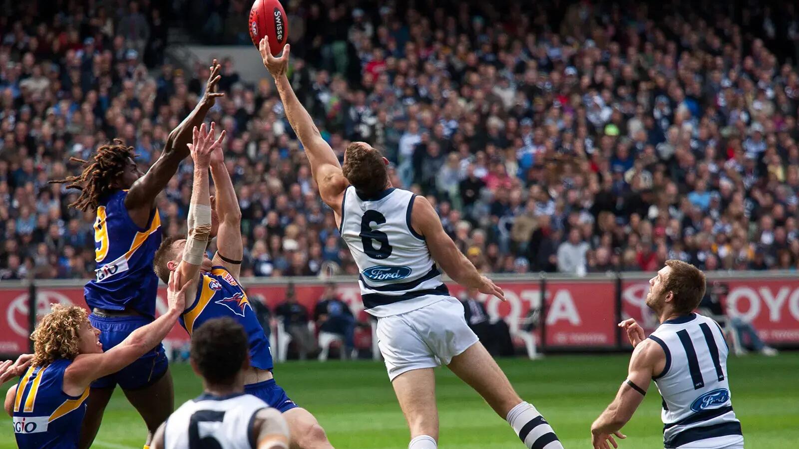 Mężczyźni grający mecz w futbol australijski na stadionie