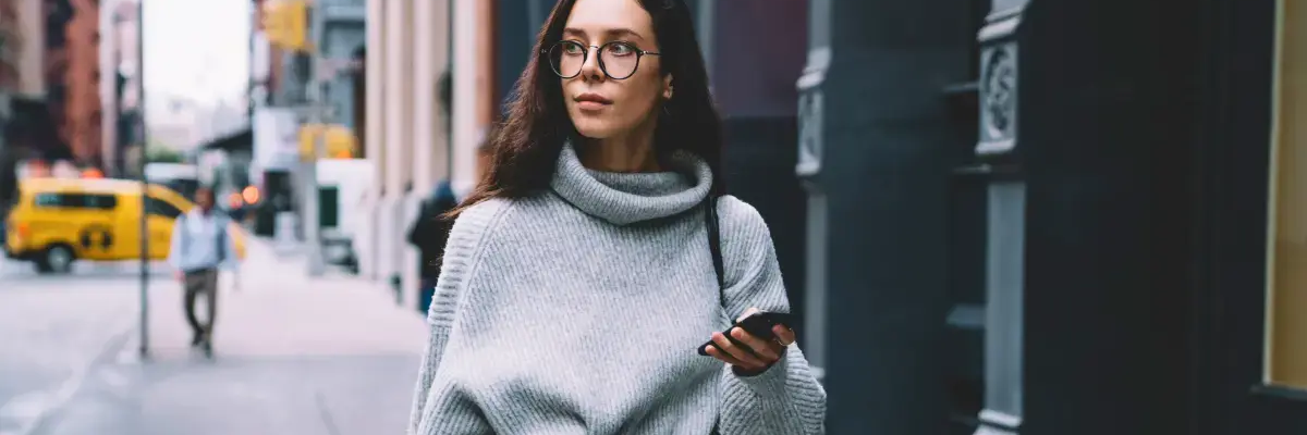 Kobieta idąca chodnikiem z telefonem w ręku