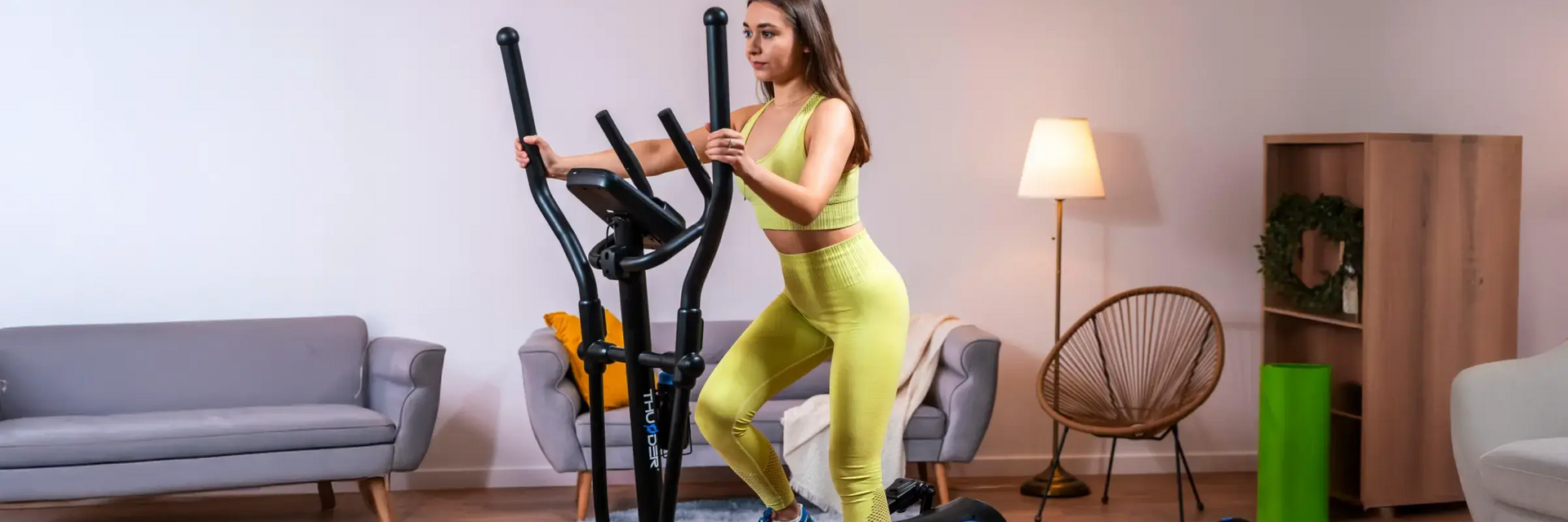 Kobieta w odzieży sportowej ćwicząca w domu na orbitreku