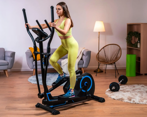 Kobieta w odzieży sportowej ćwicząca w domu na orbitreku