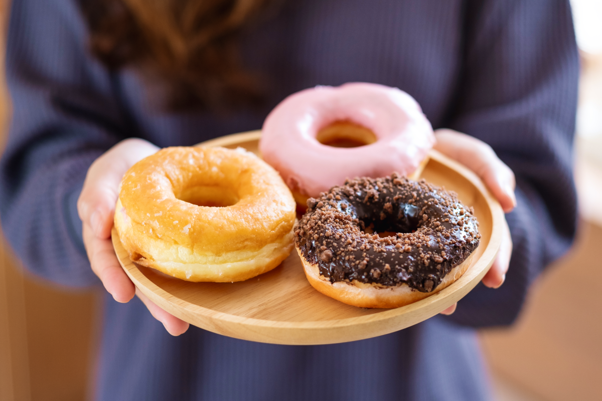 Kobieta niosąca na tacy trzy pączki