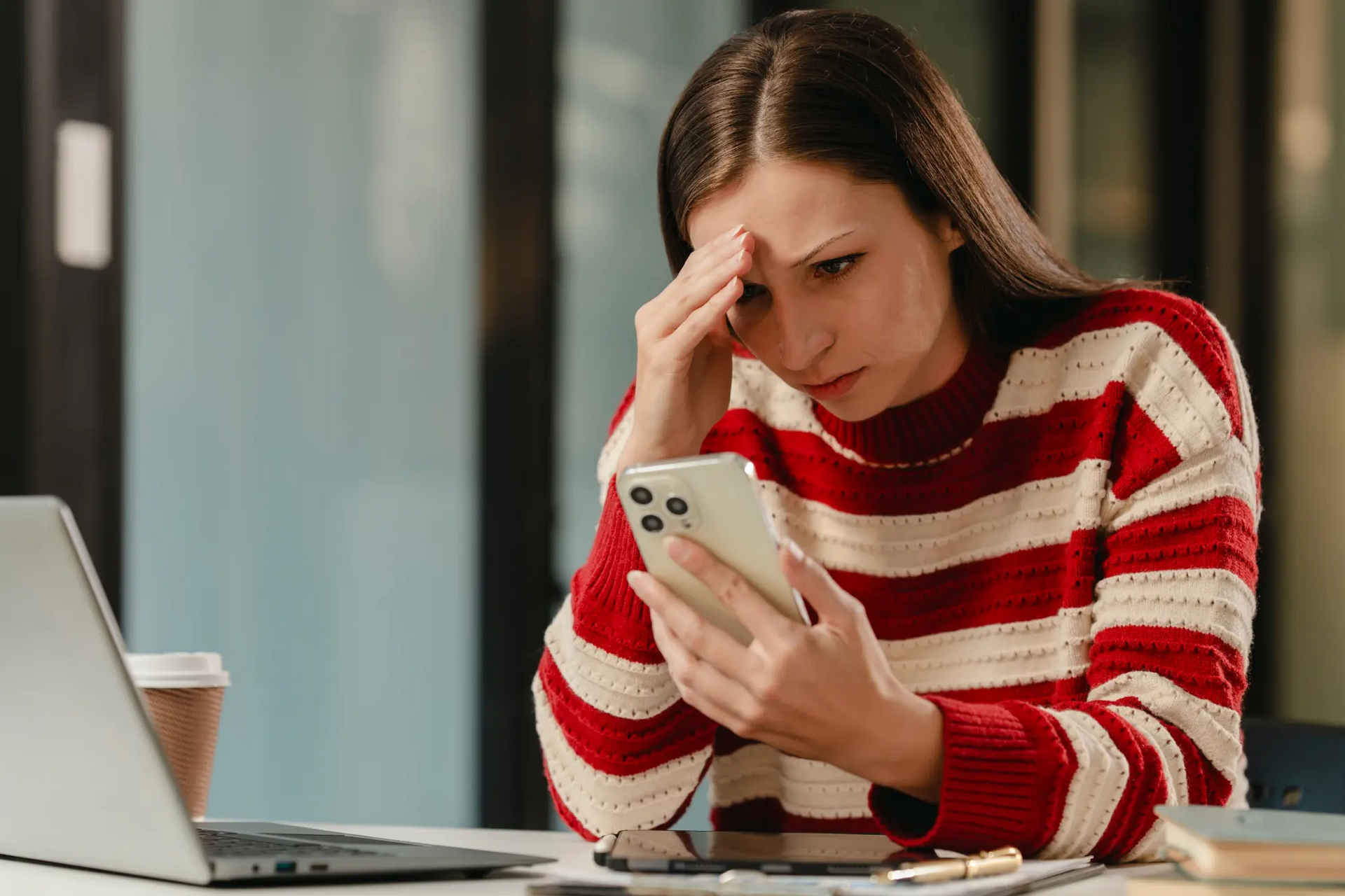 Kobieta siedząca przy biurku patrząca w telefon