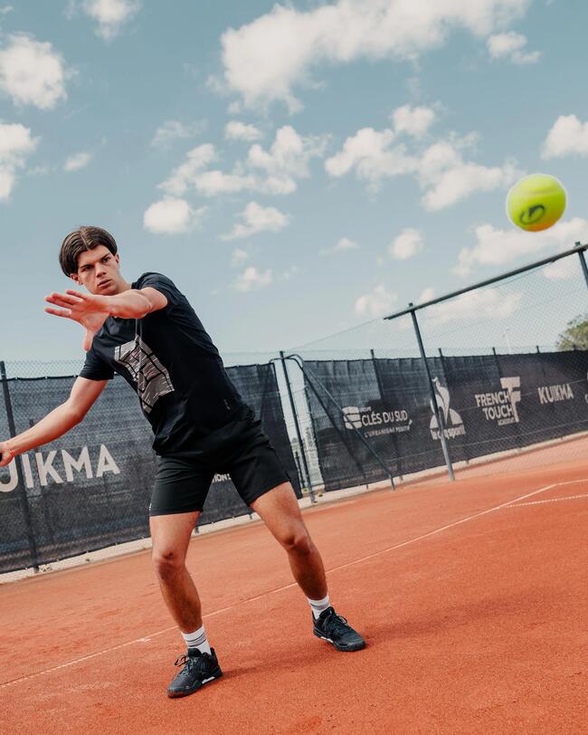 Ein junger Tennisspieler auf einem Sandplatz fokussiert einen gelben Ball in der Luft vor einem Vorhand-Schlag.