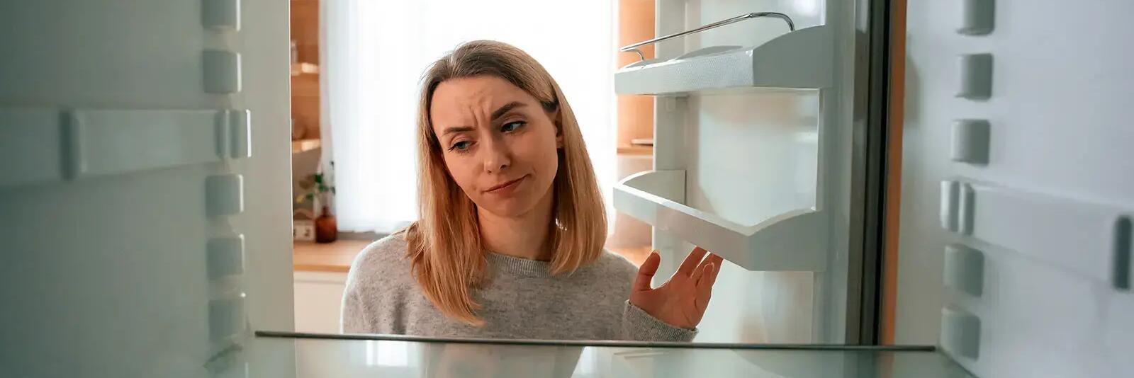 Kobieta otwierająca pustą lodówkę