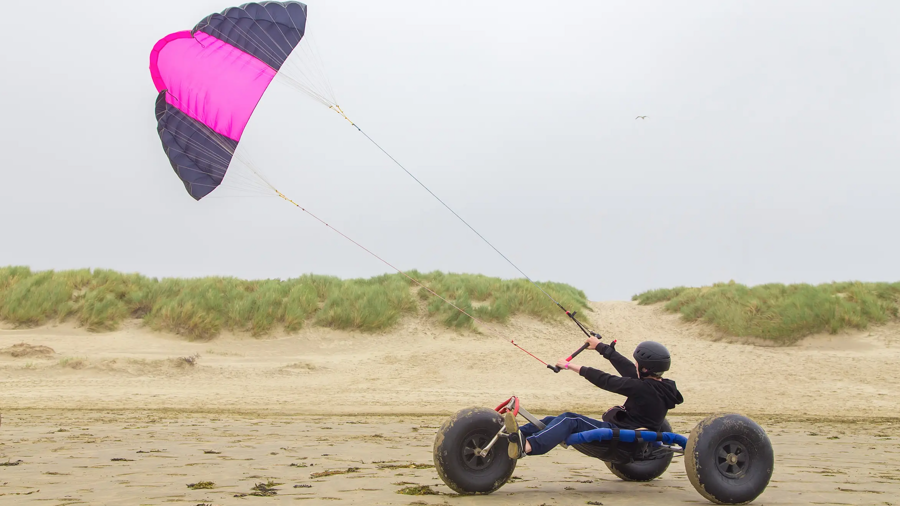 Osoba w wózku na trzech kołach z latawcem trenująca kitebuggy