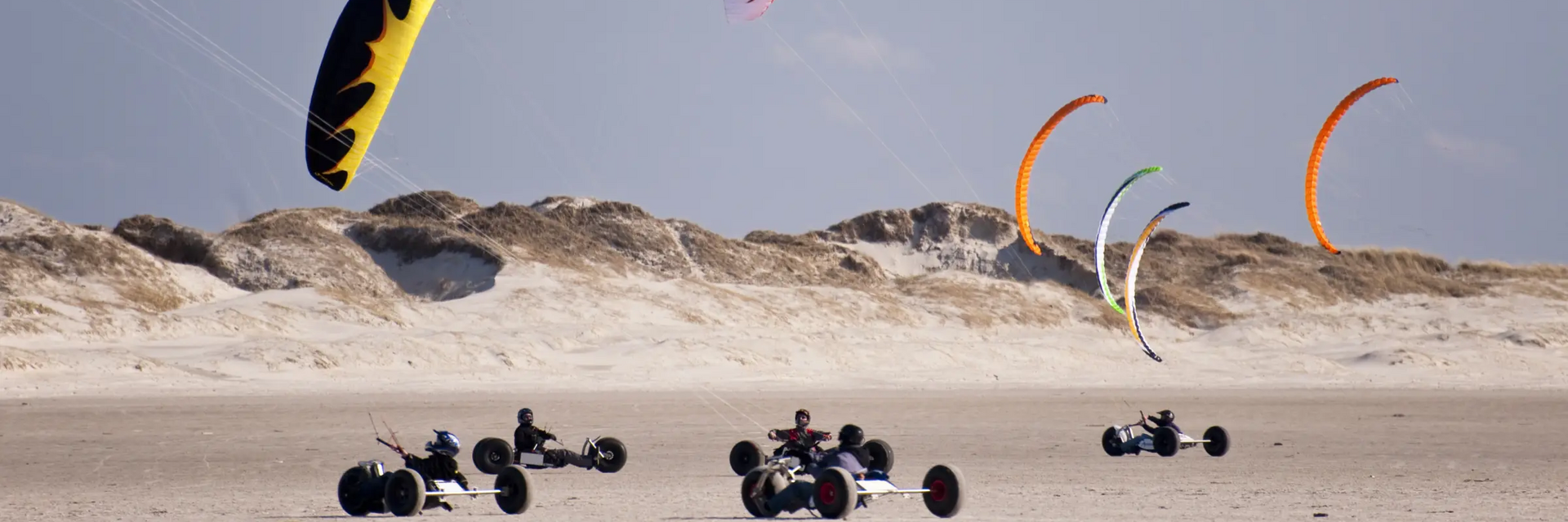Ludzie w wózkach na trzech kołach z latawcami trenujący kitebuggy