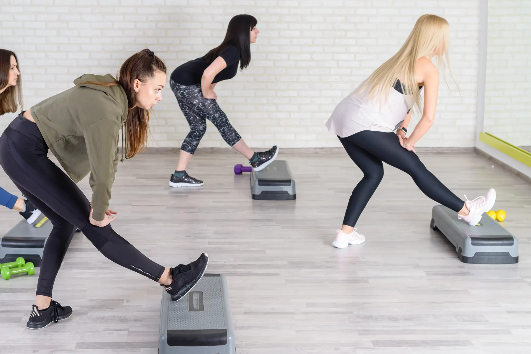 Kobiety ćwiczące na stepach w strojach sportowych