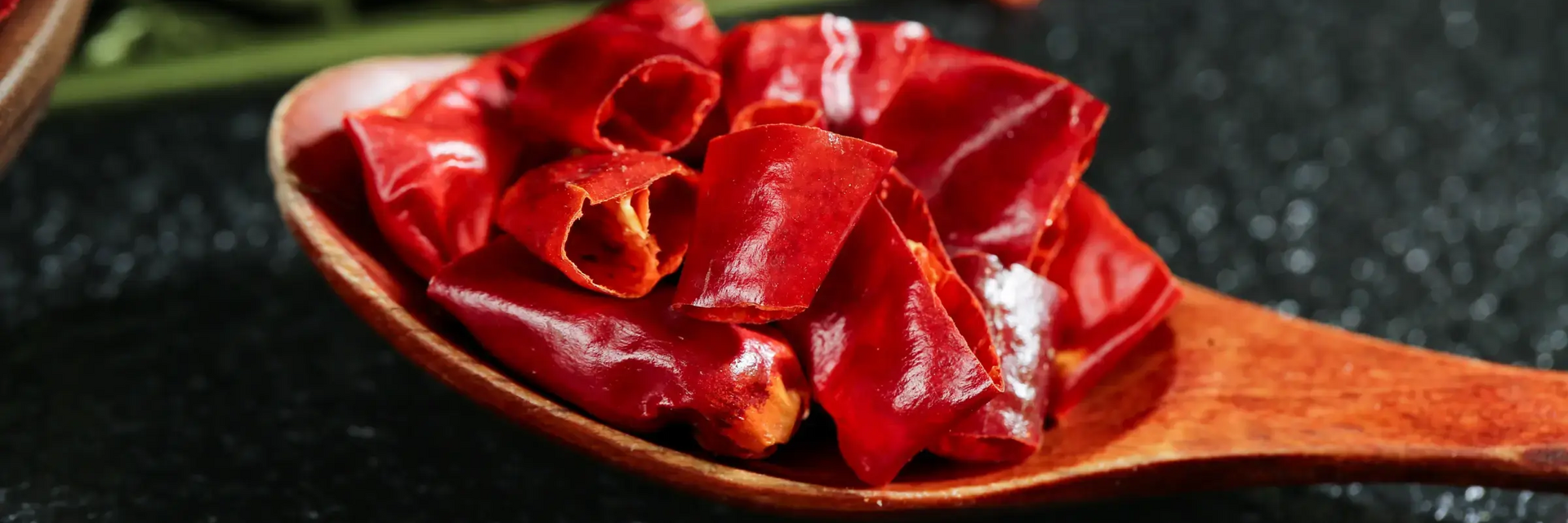 Papryczki chilli w kawałkach leżące na łyżce drewnianej