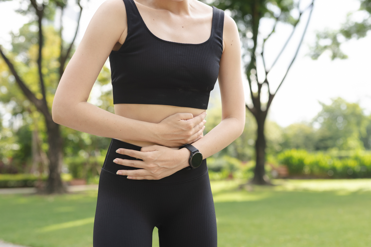 Kobieta w odzieży fitness trzymająca się za brzuch
