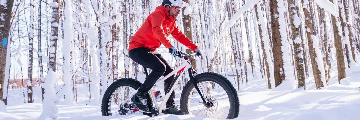 Rowerzysta jadący rowerem w lesie po śniegu