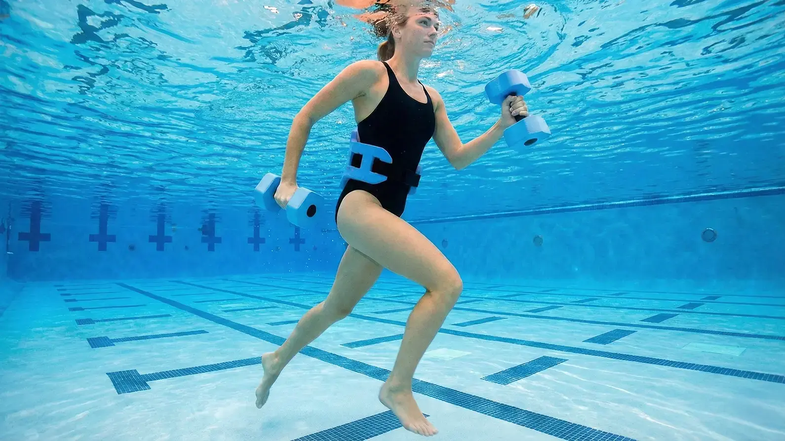Kobieta trenująca aqua jogging z obciążeniem w basenie