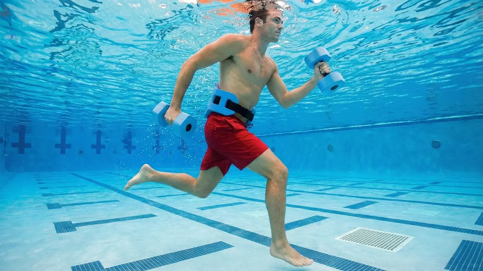 Mężczyzna trenujący aqua jogging z obciążeniem w basenie