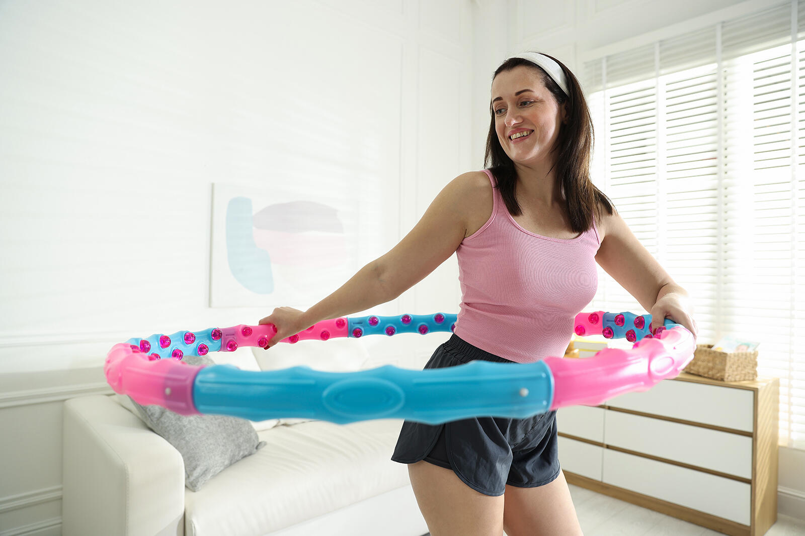 Kobieta kręcąca hula hop z obciążeniem w pokoju