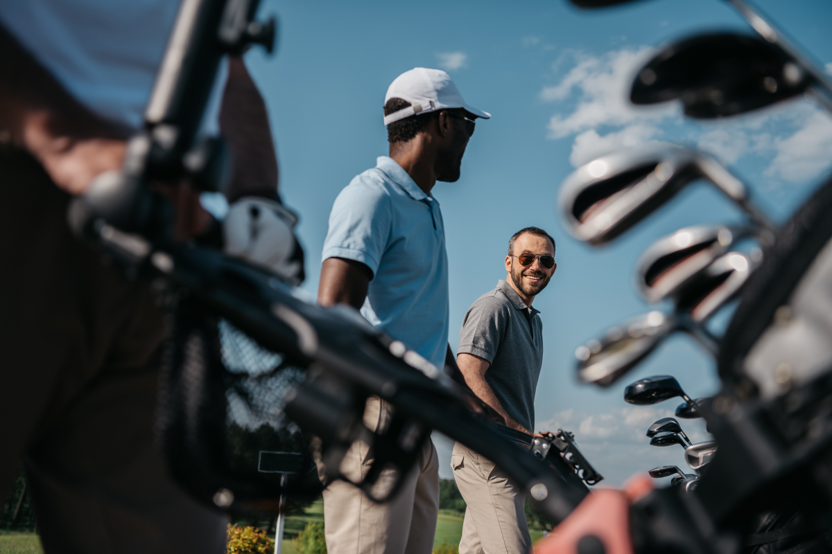 Mężczyźni idący z wózkiem golfowym