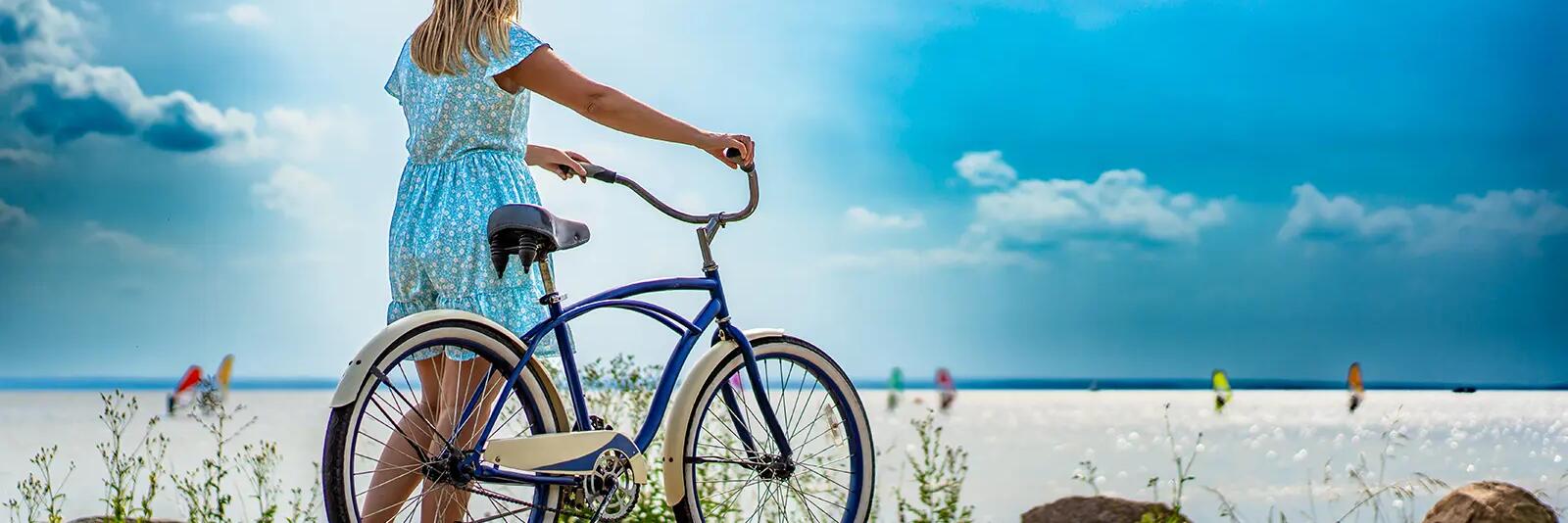 Kobieta trzymająca rower patrząca na plażę