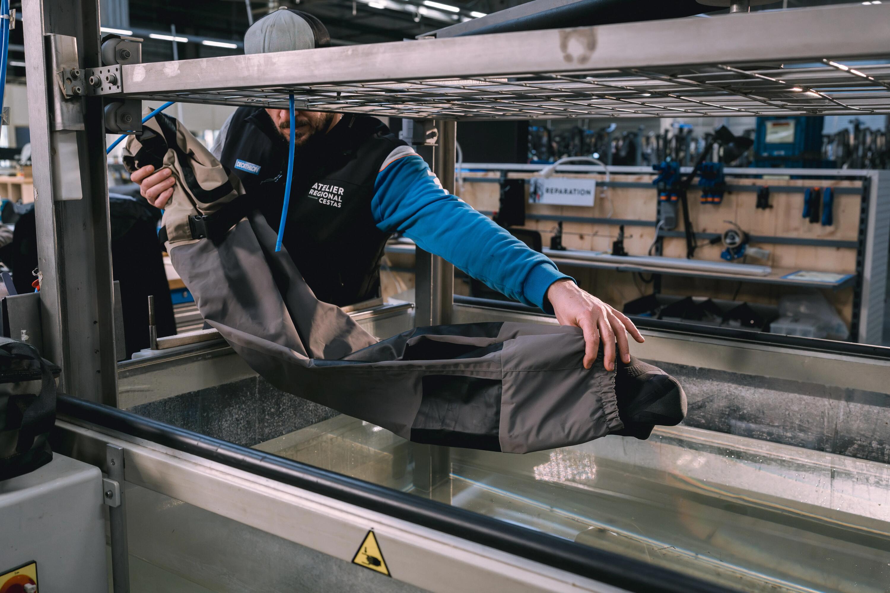 Ein Mann der eine Wathose zur Reparatur in ein Wasserbecken packt, um Löcher zu identifizieren